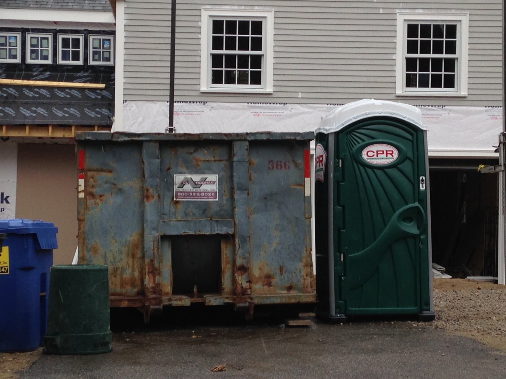 Here, the battered dumpster stands in contrast to the newness of the Port-a-potty and the renovated house itself. 