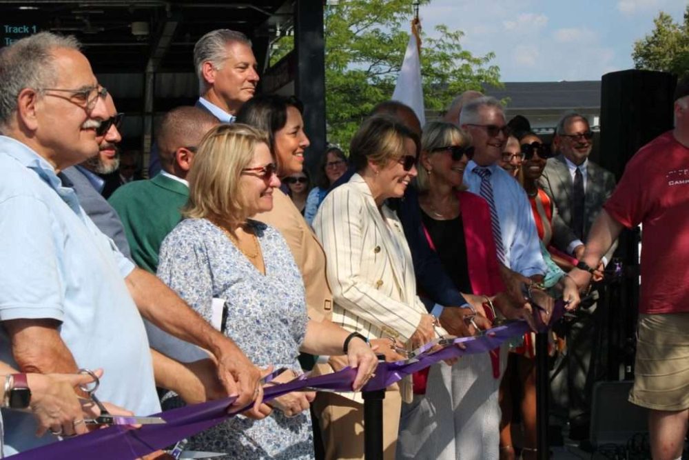 Flanked by local and state officials, Gov. Maura Healey and Lt. Gov. Kim Driscoll cutthe ribbon to officially open the Natick Center MBTA station