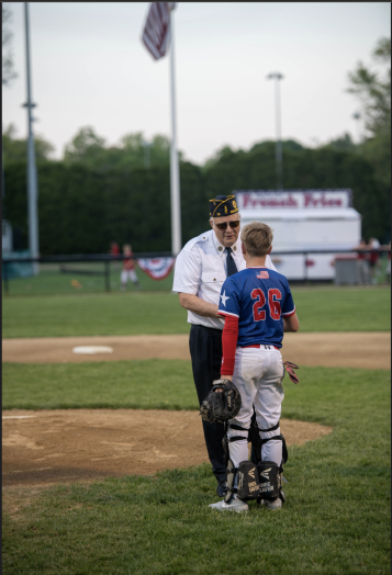 After a successful ceremonial first pitch, Sgt. Pete Jones- United States Marine Corps Veteran and Commander of the Wellesley American Legion Post 72 receives the game ball from Grayson Guigli, who proudly wears the dog tags of his great grandfather, Korean War Veteran Sgt. Ernesto Guigli, United States Army.